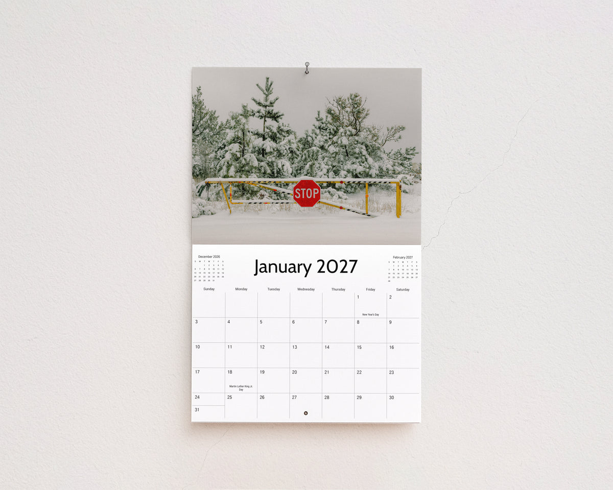 January 2027 page: snow-covered pine trees behind a stop sign and gate