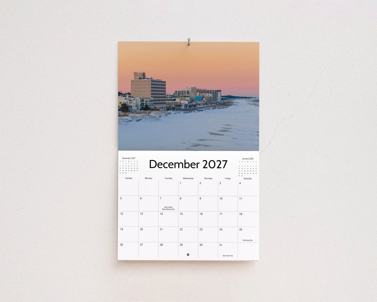 December 2027 page: snow-covered beach and boardwalk hotels under a pink winter sky