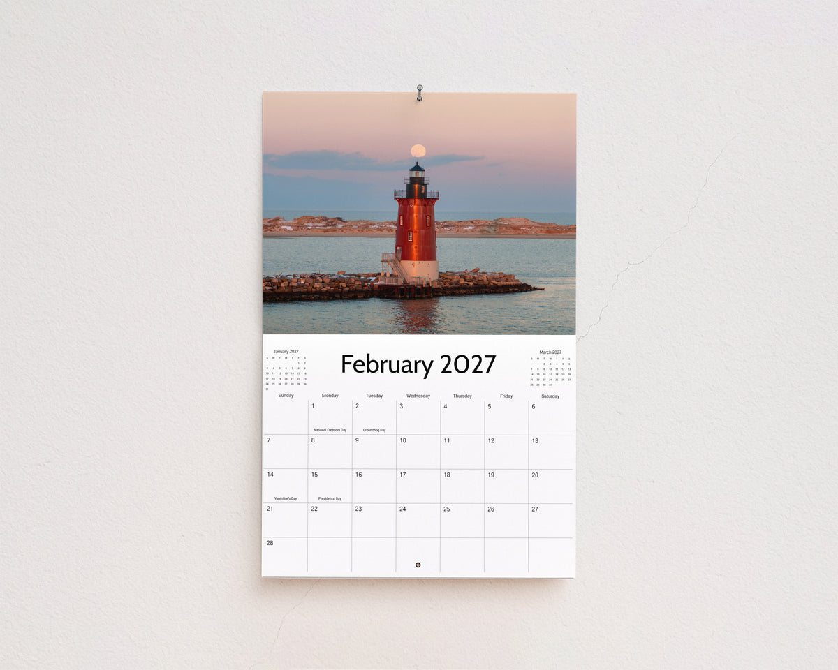 February 2027 page: red lighthouse on a rock jetty with the moon rising at dusk