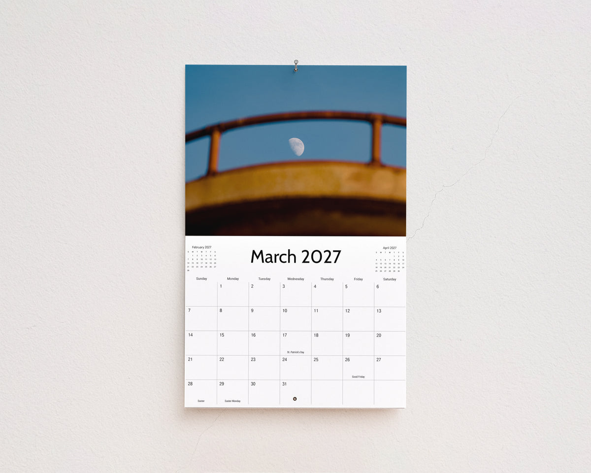 March 2027 page: the moon framed by a weathered yellow railing against a blue sky