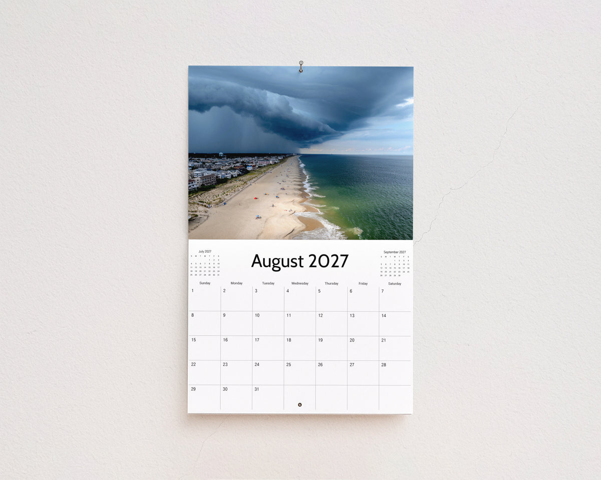 August 2027 page: aerial view of a storm rolling in over a beach town and the ocean