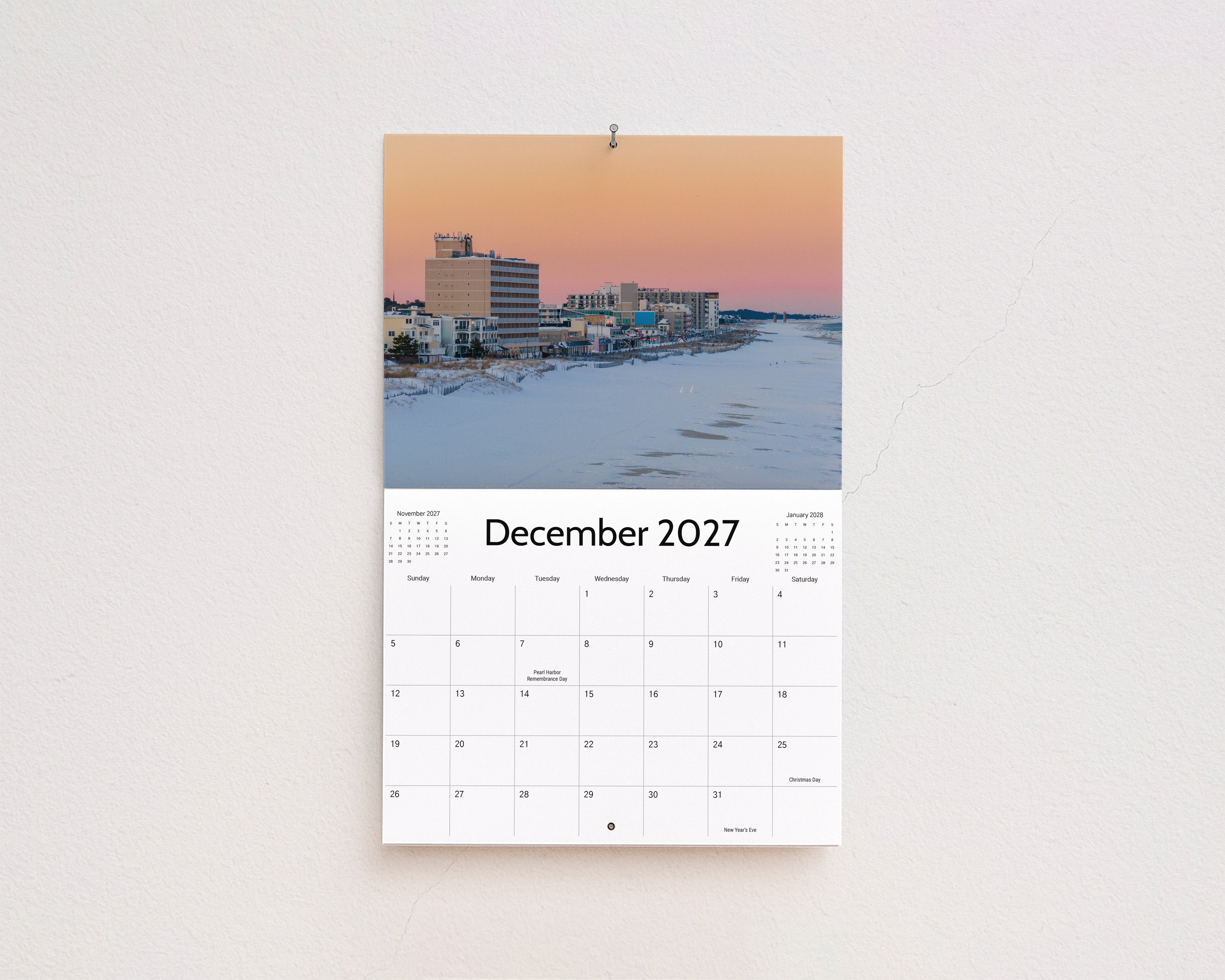 December 2027 page: snow-covered beach and boardwalk hotels under a pink winter sky