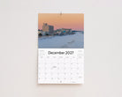 December 2027 page: snow-covered beach and boardwalk hotels under a pink winter sky