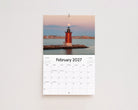 February 2027 page: red lighthouse on a rock jetty with the moon rising at dusk