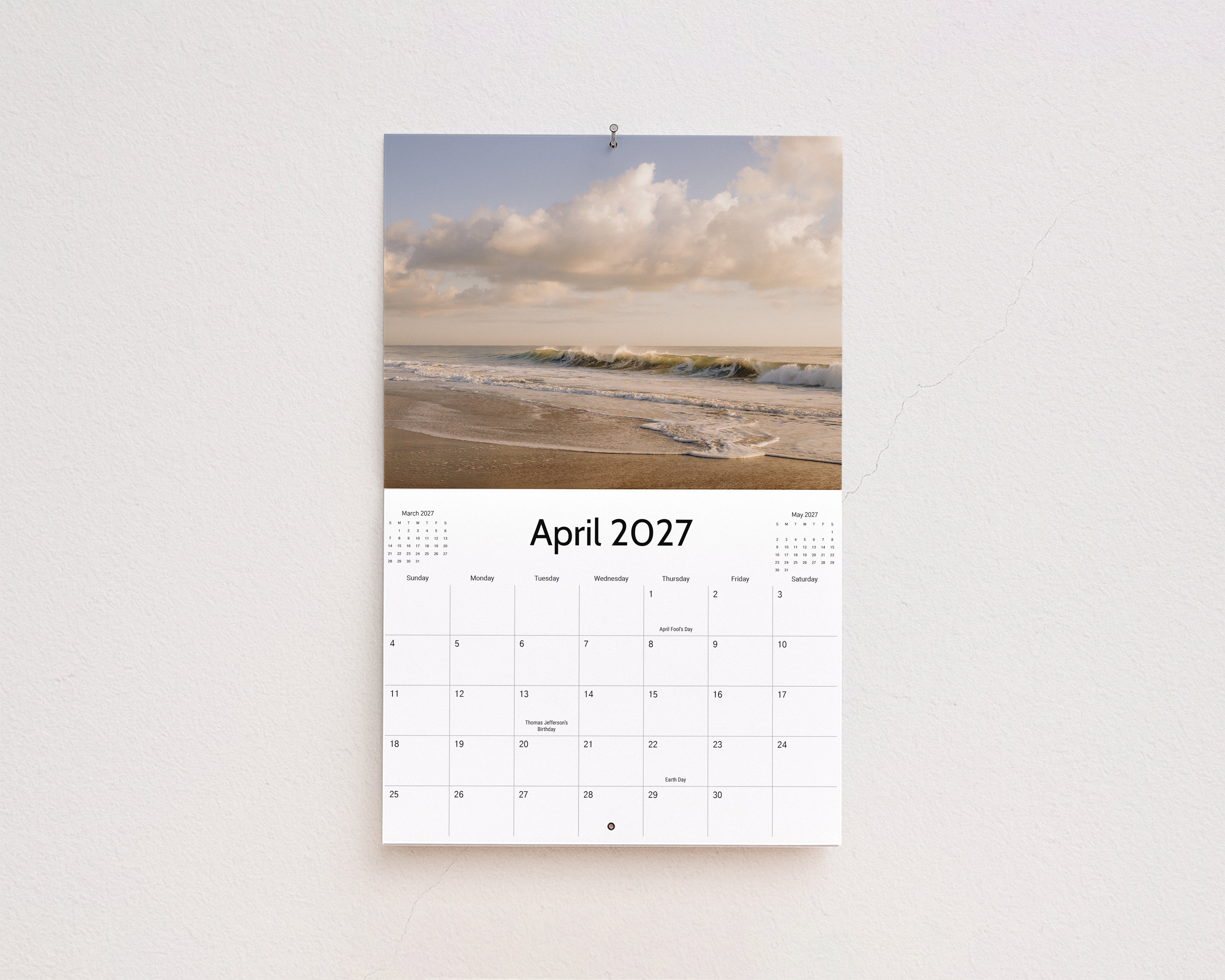 April 2027 page: waves rolling onto the beach under soft white clouds